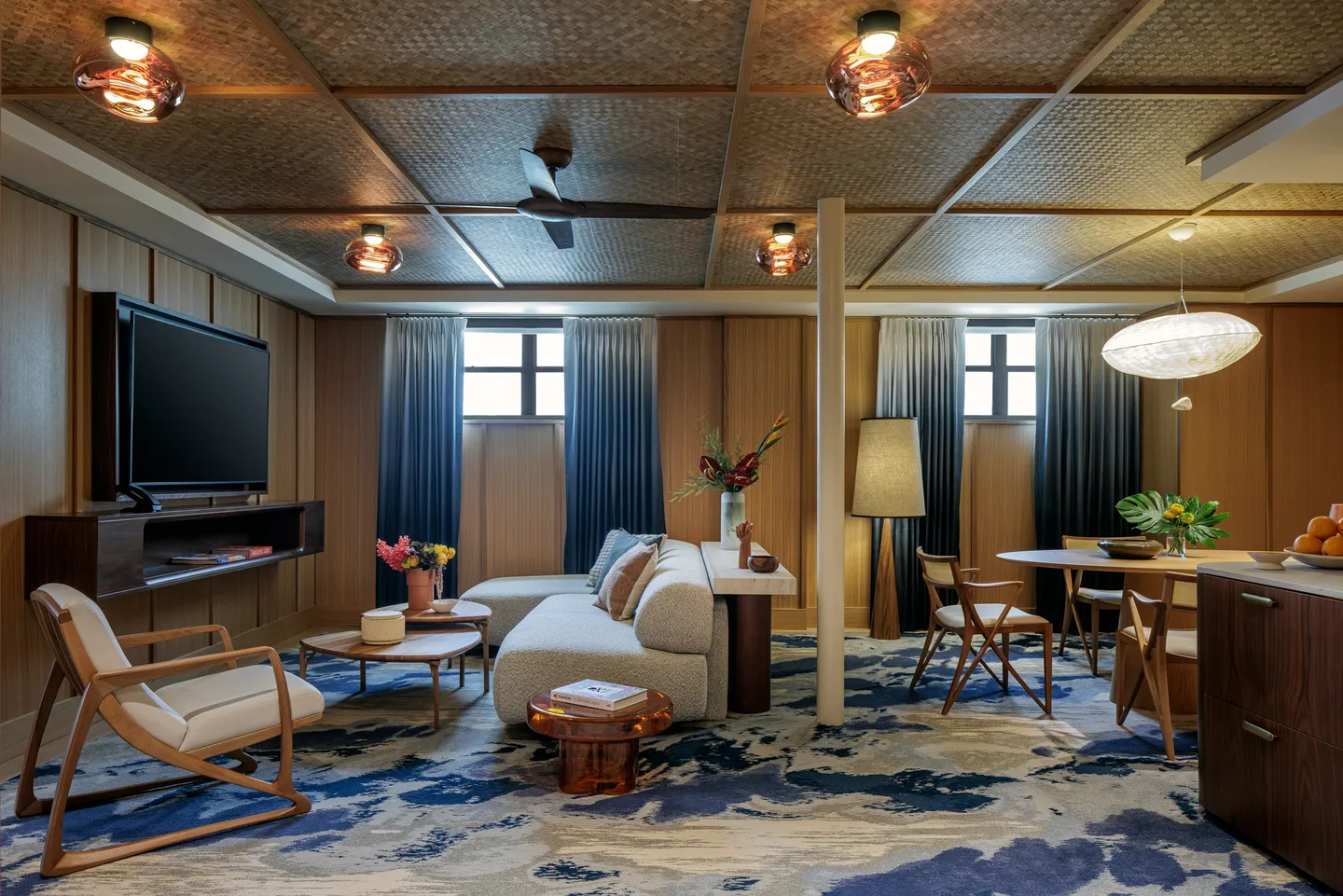 A suite living area with a sofa, side tables and daylight through large windows